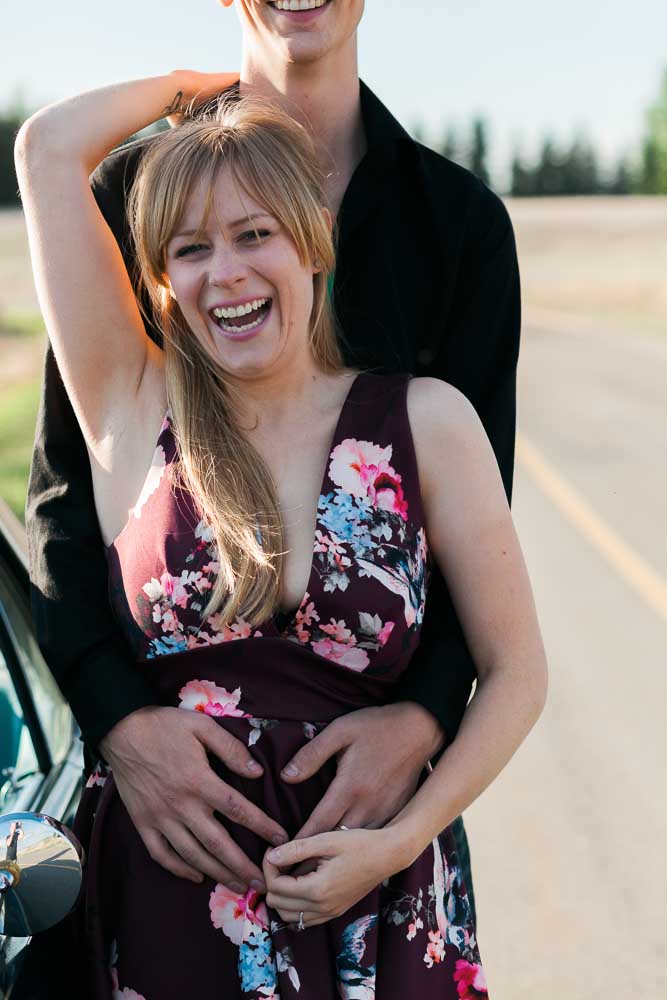 woman smiling at camera with man hugging her from behind tips to be comfortable in your engagement photos