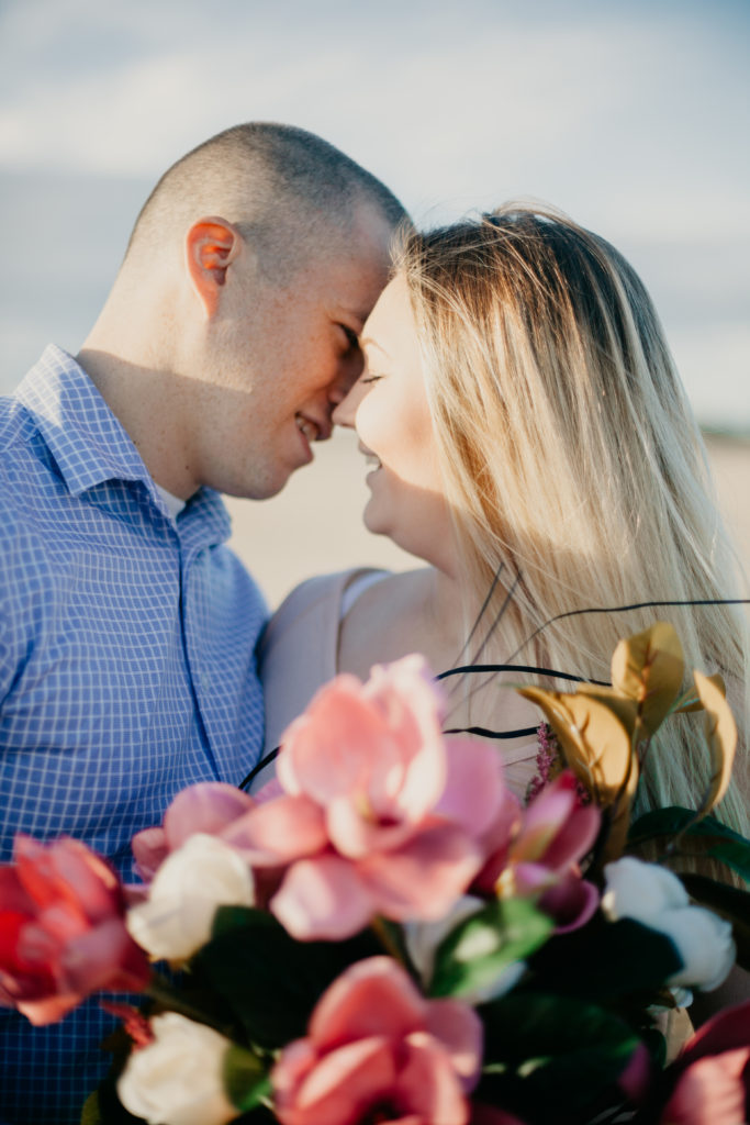 couple almost kissing with bouquet of flowers in foreground