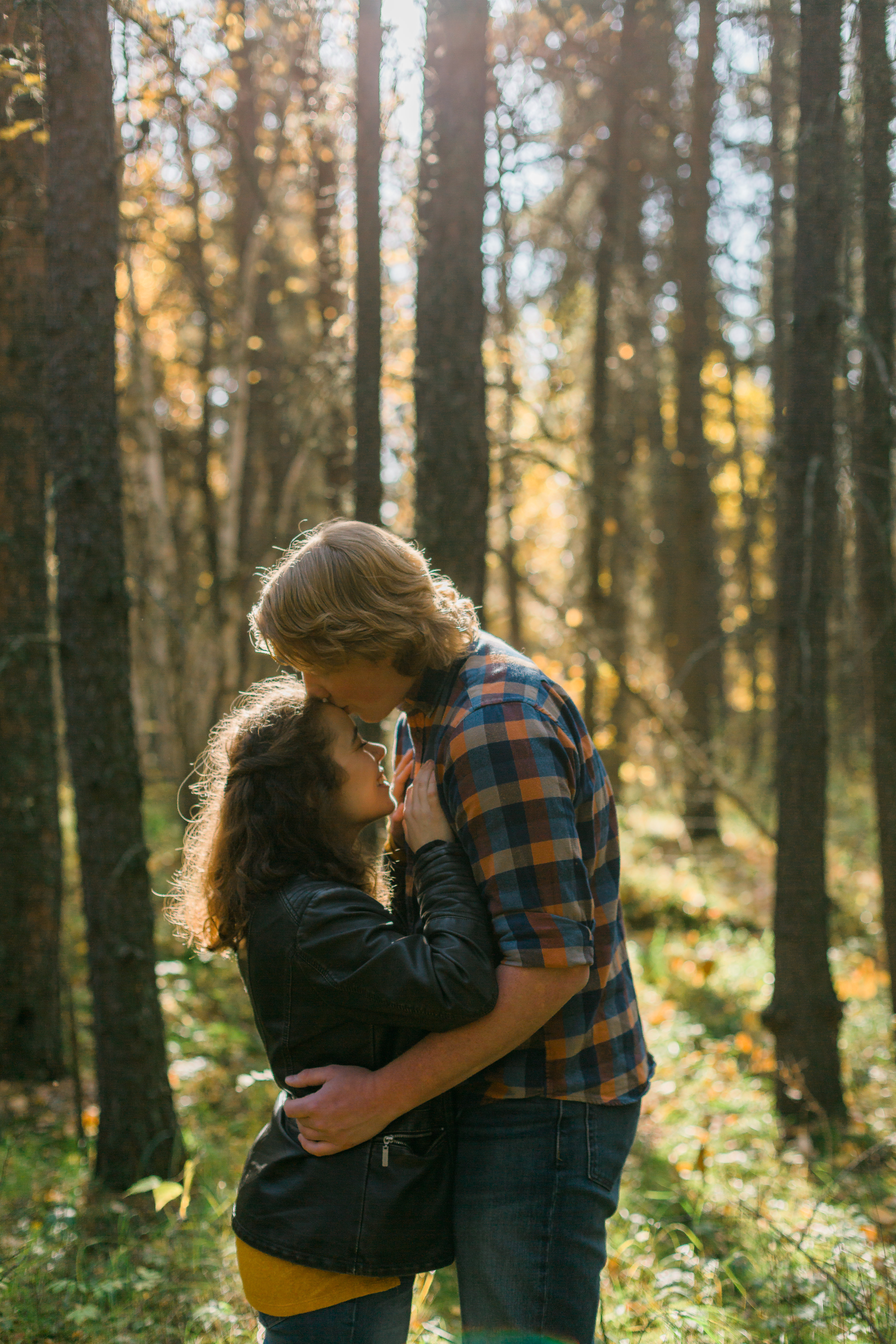 kiss on forehead with sun haze through trees